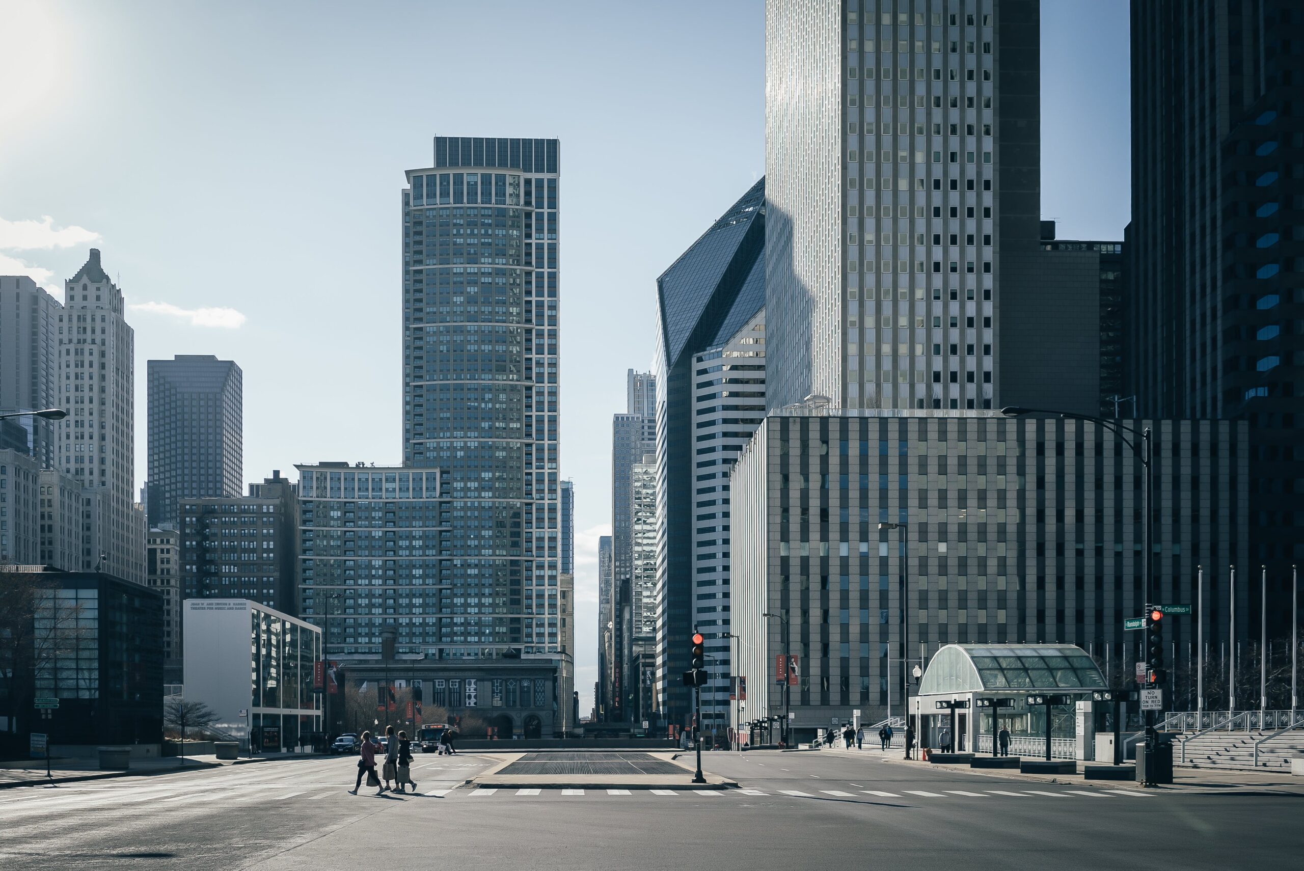City skyline with modern office towers and pedestrians at a downtown intersection.